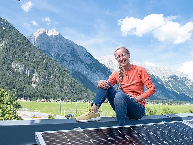 Olympiaworld Innsbruck Eine Frau sitzend auf einem Dach mit Photovoltaikanlage