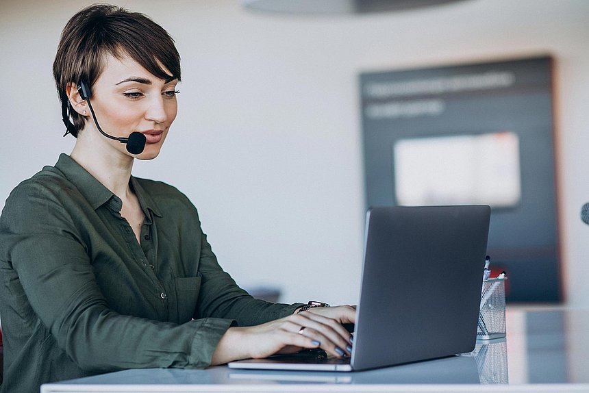 Olympiaworld Innsbruck Dame mit Headset und Laptop bei der Kundenbetreuung