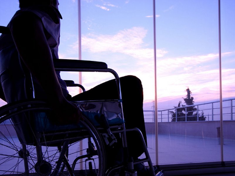 Olympiaworld Innsbruck Person in einerm Rollstuhl mit Blick durch ein großes Glasfenster